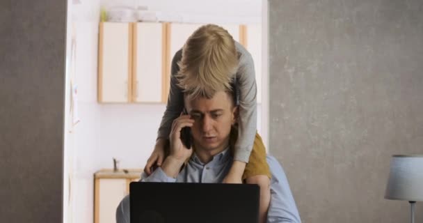 Il figlioletto impedisce al padre di lavorare a casa. Il giovane papà è freelance durante l'auto-isolamento. Lavoro a distanza. — Video Stock