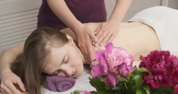 Egy női masszőr kezei finoman masszírozzák vissza egy gyönyörű fiatal nőnek. Kellemes spa szalon, gondoskodás a test — Stock videók