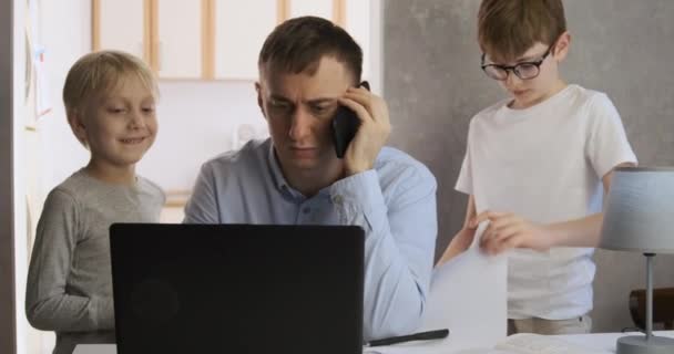 Padre trata de trabajar remotamente con sus hijos en casa. Los hijos interfieren con el trabajo de sus padres. Familia sobre el autoaislamiento. — Vídeo de stock