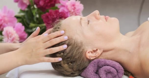 Young woman receiving head massage at spa center. Masseuse doing relaxing head massage at wellness center. — Stock Video