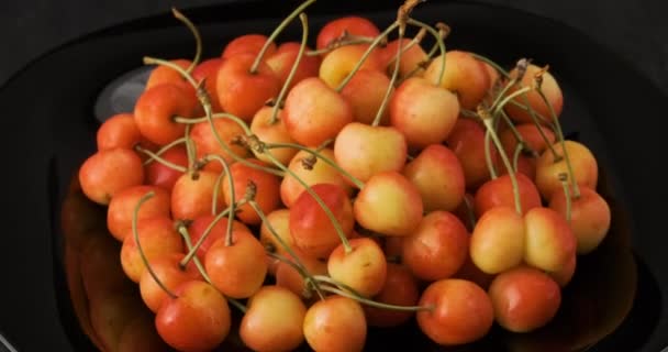 Cerejas maduras amarelas na chapa preta redonda. Bagas frescas de verão. Mesa giratória giratória no sentido horário tiro. Rotativa de vídeo. — Vídeo de Stock