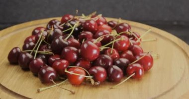  Yuvarlak ahşap zemin üzerinde taze kırmızı olgun kirazlar. Yaz meyveleri. Saat yönünde döner döner döner döner tabla atışı. Döndürme videosu. 