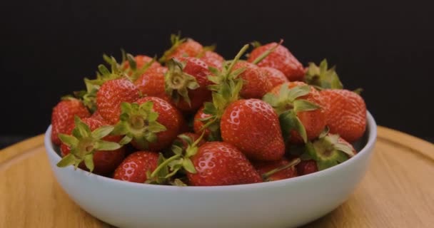 Čerstvé jahody v šedém talíři na černém pozadí. Sezónní červené bobule. Točí se video. Pohyb smyčky. — Stock video