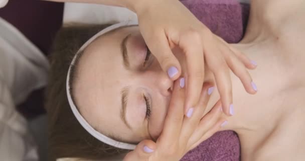 Massagem facial, área da prega nasal. As mãos do massagista suavemente fazem uma massagem facial modelar. Jovem mulher em um salão de beleza — Vídeo de Stock