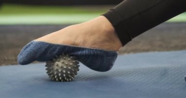 Ayak masajı için masaj aleti kullanan bir kız. Kendi kendine masaj. MYK. Miyofasyal tahliye. Myofascial topu. 