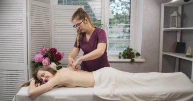 Gülümseyen güzel kadın masajdan hoşlanır. Usta profesyonel masaj yapıyor, spa salonu. Rahatlatıcı ve iyileştirici prosedür