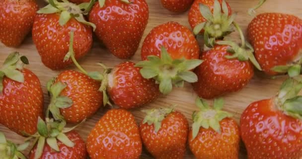 Fresas frescas maduras giran sobre una superficie de madera. Primeros planos de bayas de verano. Rotación de vídeo, vista superior — Vídeos de Stock