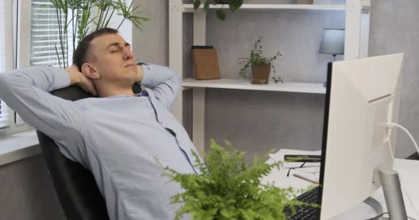 Ředitel se unaveně protáhne v křesle. Pracovník mužské kanceláře v kanceláři odpočívá v křesle. — Stock video