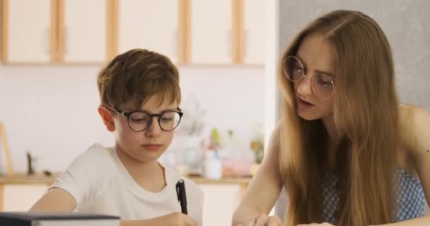 Madre e hijo están haciendo los deberes juntos. Enseñanza en casa. Tutor trabaja con el estudiante. — Vídeos de Stock