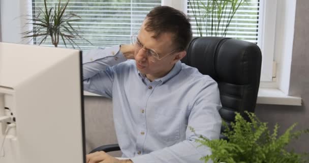 Male office employee suffers from neck pain and fatigue. Director sits in leather chair and rubs his neck. — Stock Video