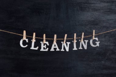 Temizlik kelimesi siyah arka planda çamaşır mandallarıyla ipte asılı.