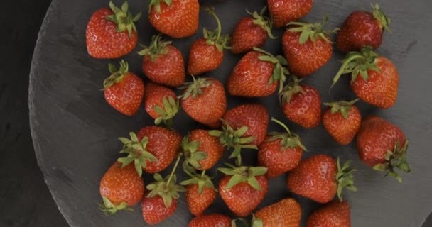 Vista de arriba hacia abajo del plato con fresas frescas en el plato redondo negro. Bayas de verano. Rotación de vídeo. Movimiento de bucle. — Vídeos de Stock