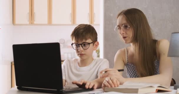 母亲和孩子们正在笔记本电脑上做作业。）（年轻的老师在和男孩一起学习. — 图库视频影像