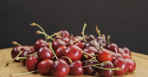 Rotating wooden plate with red ripe cherries. Fresh appetizing summer fruit close-up. Rotating video. 