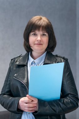 Deri ceketli genç bir kadının elinde belgeler var. Motosiklet ceketli iş kadını. Modern iş kadını.