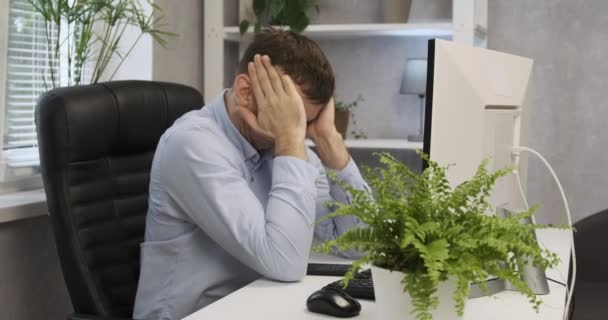 Tânărul director din biroul lui freacă ochii obosit. Tânăr om de afaceri care lucrează la calculator, adormind în birou . — Videoclip de stoc