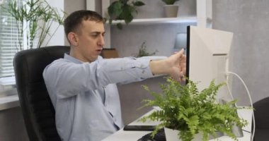 Genç ofis çalışanı yorgun ve sandalyesinde geriniyor. Ofis müdürü geç saatlere kadar çalışıyor.