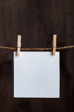 Ahşap arka planda çamaşır mandallarıyla asılı beyaz boş notlar. Uzayı kopyala Mesajın için yer aç. Dikey çerçeve.