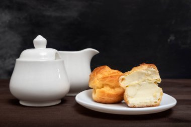 Kremalı pasta, beyaz tabak ve çay seti. Hamur tatlısı. Çay için pişiriyorum..