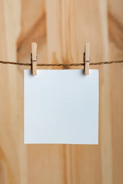 白色空白纸片 用绳子上的衣针挂在木制背景上 复制空间 垂直框架 — 图库照片