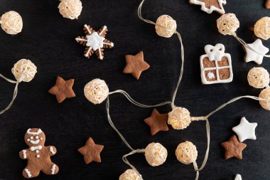 Çelenk ve Noel kurabiyeleri siyah arkaplanda şekerli krema.
