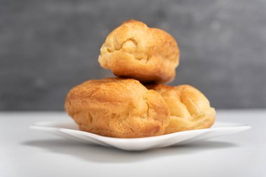 Hassas profiteroller ya da çay tabağında krema olmayan eklereler. Gri arkaplan