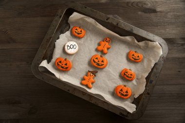 Balkabağı şeklinde parlak turuncu kurabiyeler ve komik adamlar bir yemek kabında yatıyor. Lezzetli portakallı zencefilli kurabiye. Cadılar Bayramı. Kutla