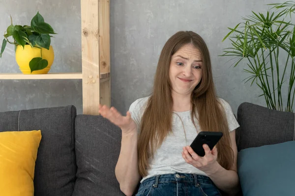 Mujer Joven Está Sentada Sofá Con Teléfono Lanza Sus Manos —  Fotos de Stock