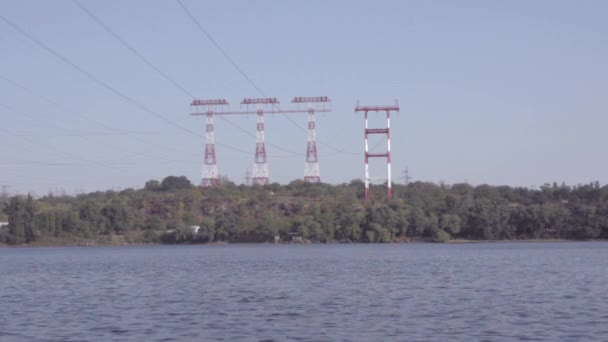 Μηχανοκίνητο σκάφος επιπλέει στις όχθες του ποταμού, στο πλαίσιο της πύργους μετάδοσης υψηλής τάσης — Αρχείο Βίντεο