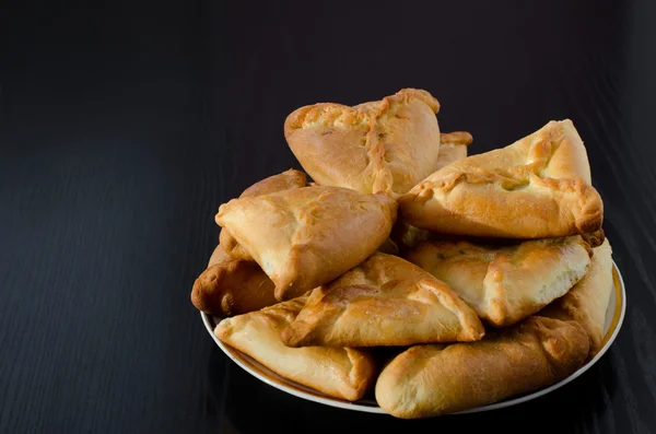 Une assiette avec des tartes fraîches sur une table en bois noir — Photo