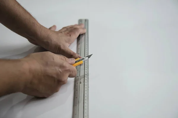 Man using measure hand tool doing wallpaper cutting work in home construction site, people with hand tool object concept