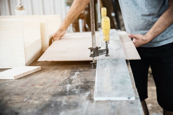 Carpenter working with wood furniture product preparation using hand tools and machine table station
