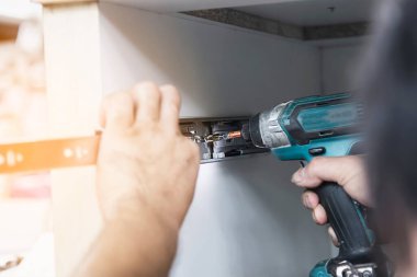 Carpenter elektrikli tornavida kullanarak mobilya montajı ile çalışıyor - mekanda el aletleri konseptini kullanarak teknisyen