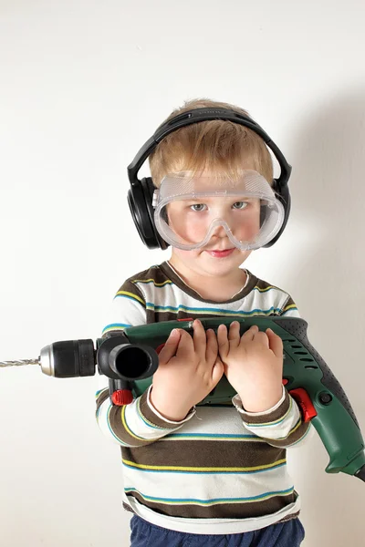 Mały chłopiec z okularów ochronnych i słuchawki, trzymając wiertła — Zdjęcie stockowe