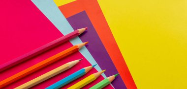 Renkli kalemler, simetrik olarak sıralanmış, renkli kağıtlar, karton