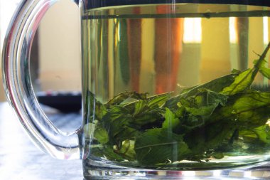 Cam bardakta naneli çay yakın.