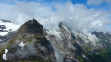 Dağ zirveleri bulutlarla, gökyüzüyle, dağıyla, buharla, karla kaplıdır.