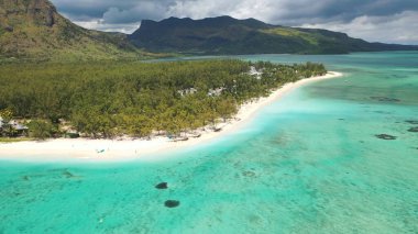 Kumlu tropik sahil, okyanus, bulutlu gökyüzü, dağlar, kayalar