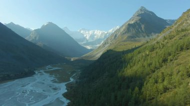 Yandan güneş ışığı parlıyor ve dağları ve vadiyi sular altında bırakıyor.