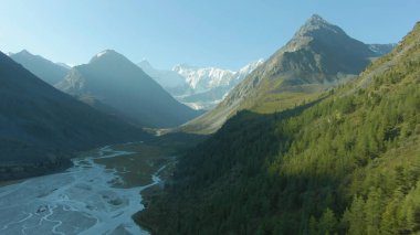 Yandan güneş ışığı parlıyor ve dağları ve vadiyi sular altında bırakıyor.