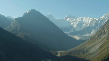 Yandan güneş ışığı parlıyor ve dağları ve vadiyi sular altında bırakıyor.