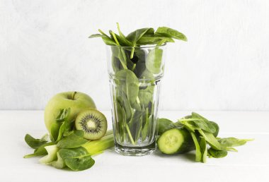 Güler yüzlü için malzemeler: ıspanak, kivi, elma, kereviz bir whit üzerinde