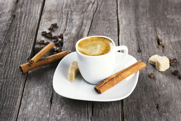 Kopje koffie met kaneel en suiker op een donkere houten pagina — Stockfoto