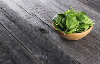 Koyu ahşap arka plan üzerinde kase ıspanak yaprakları
