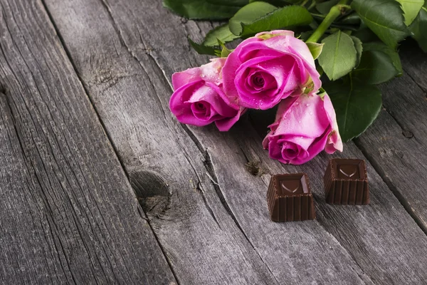 Pink roses and chocolates in form of heart against a dark backgr — Stock Photo, Image