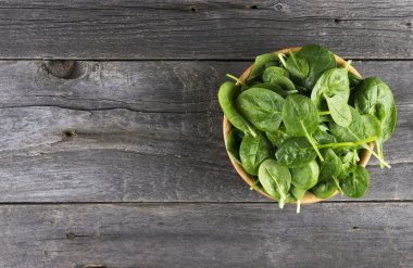 Koyu ahşap arka plan üzerinde kase ıspanak yaprakları
