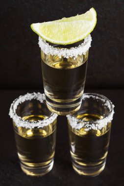 Koyu arkaplanda tuz ve limonlu tekila.