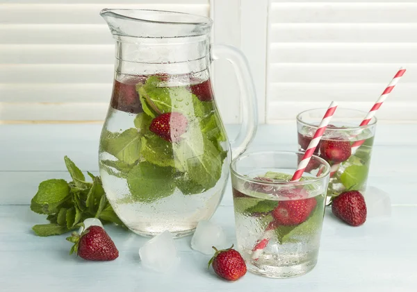 Bebida fría de verano con fresa, menta y hielo en un respaldo ligero —  Fotos de Stock