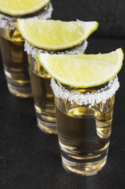 Koyu arkaplanda tuz ve limonlu tekila.