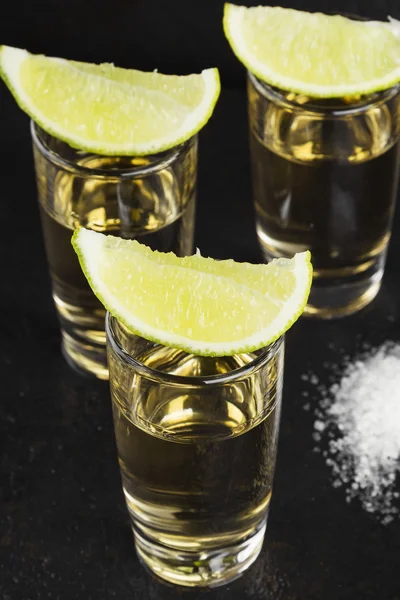 Tequila com sal e limão sobre um fundo escuro — Fotografia de Stock